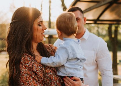 a man and woman holding a baby in a park
